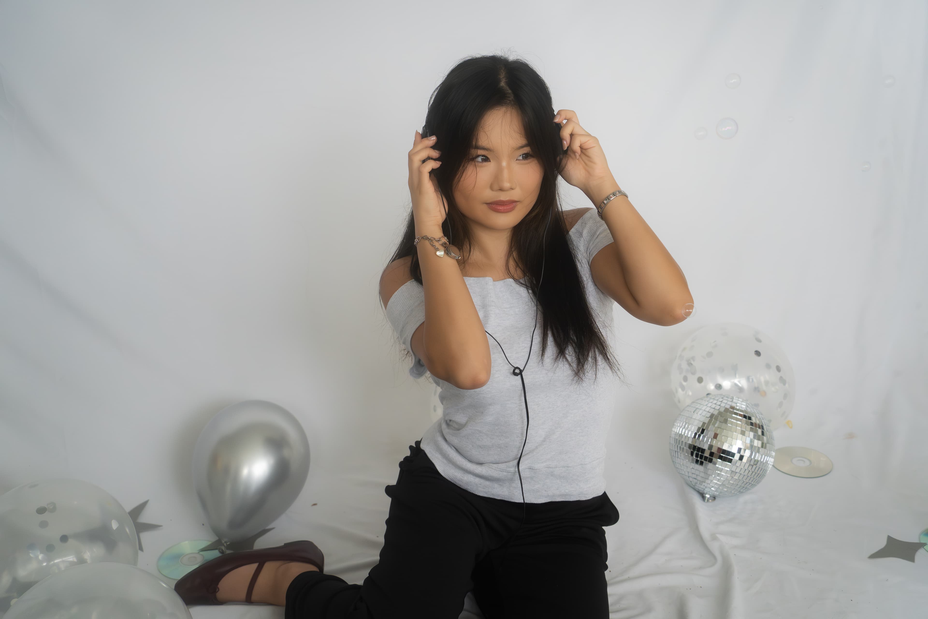 Chloe sitting beside a disco ball and balloons